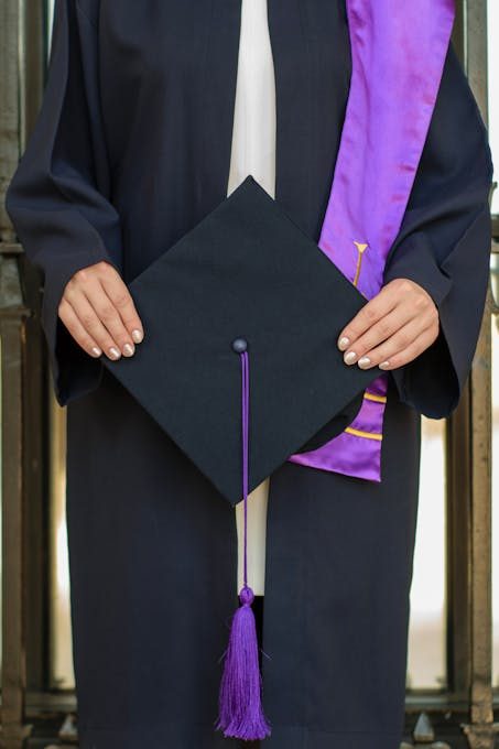 Close-up of a graduate holding a cap, symbolizing academic achievement at a ceremony.