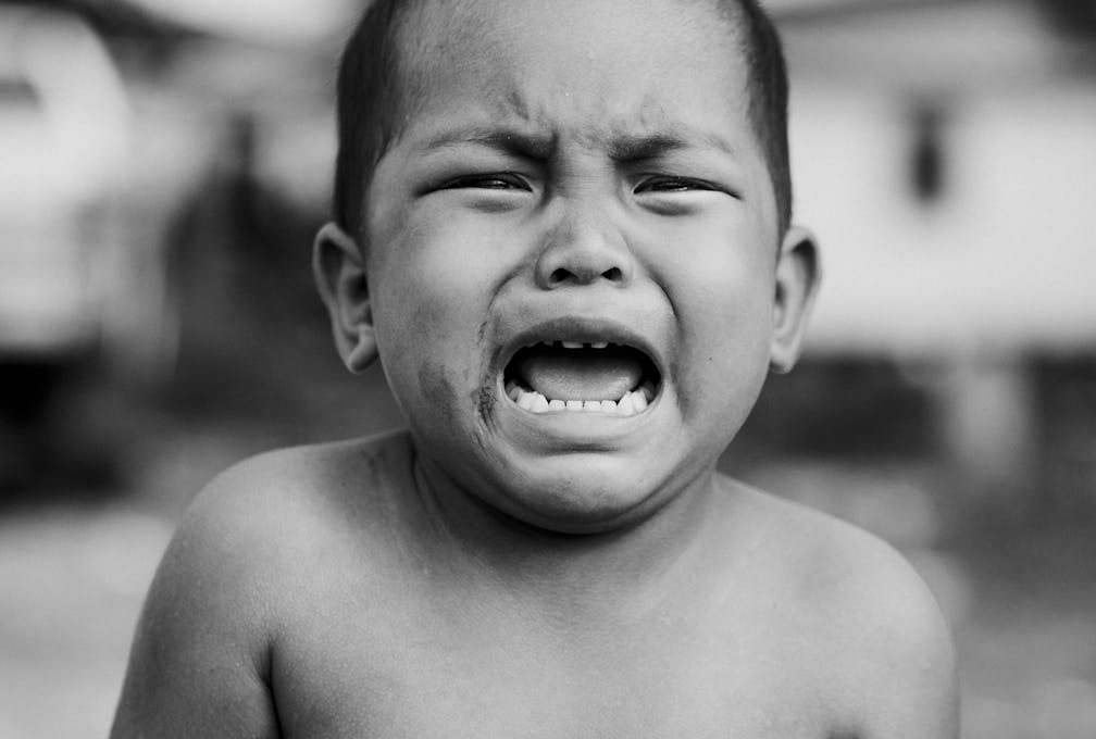 Heartfelt portrait of a young child crying, showcasing raw emotion in black and white.