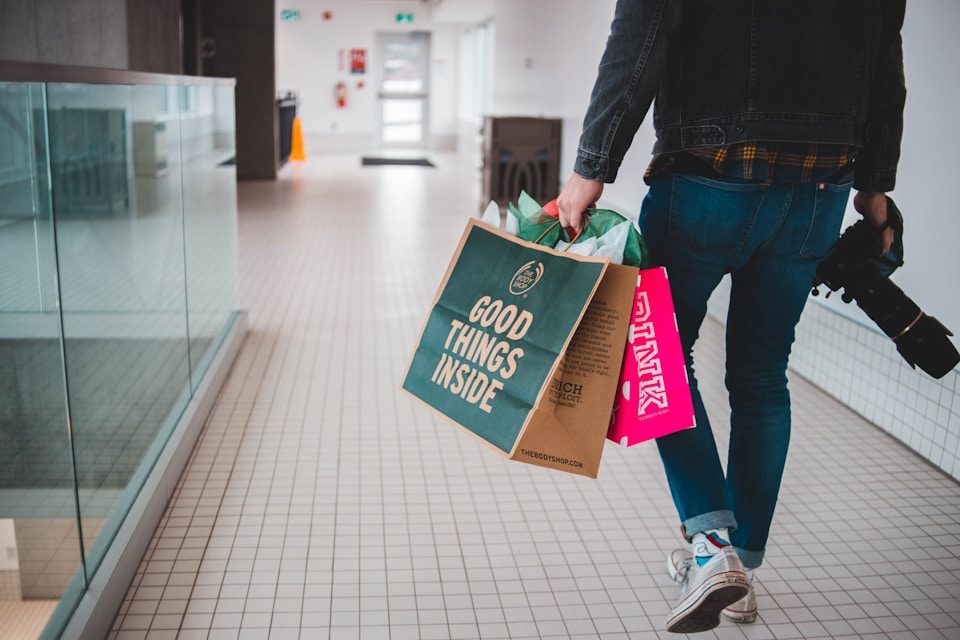 Mengapa Kita Sering Belanja Online? person walking while carrying a camera and paper bags