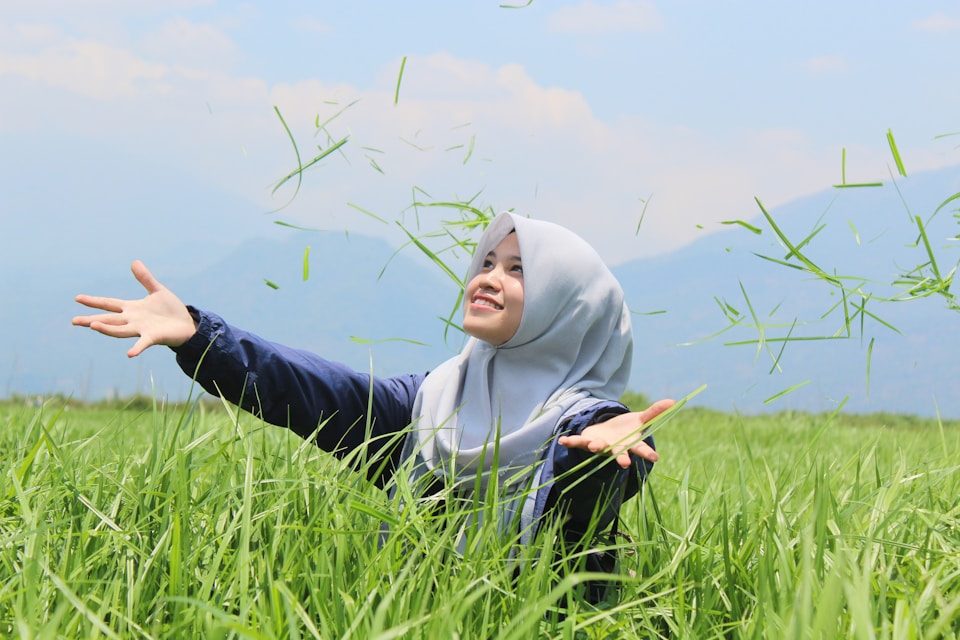 woman standing on grain field throwing grasses